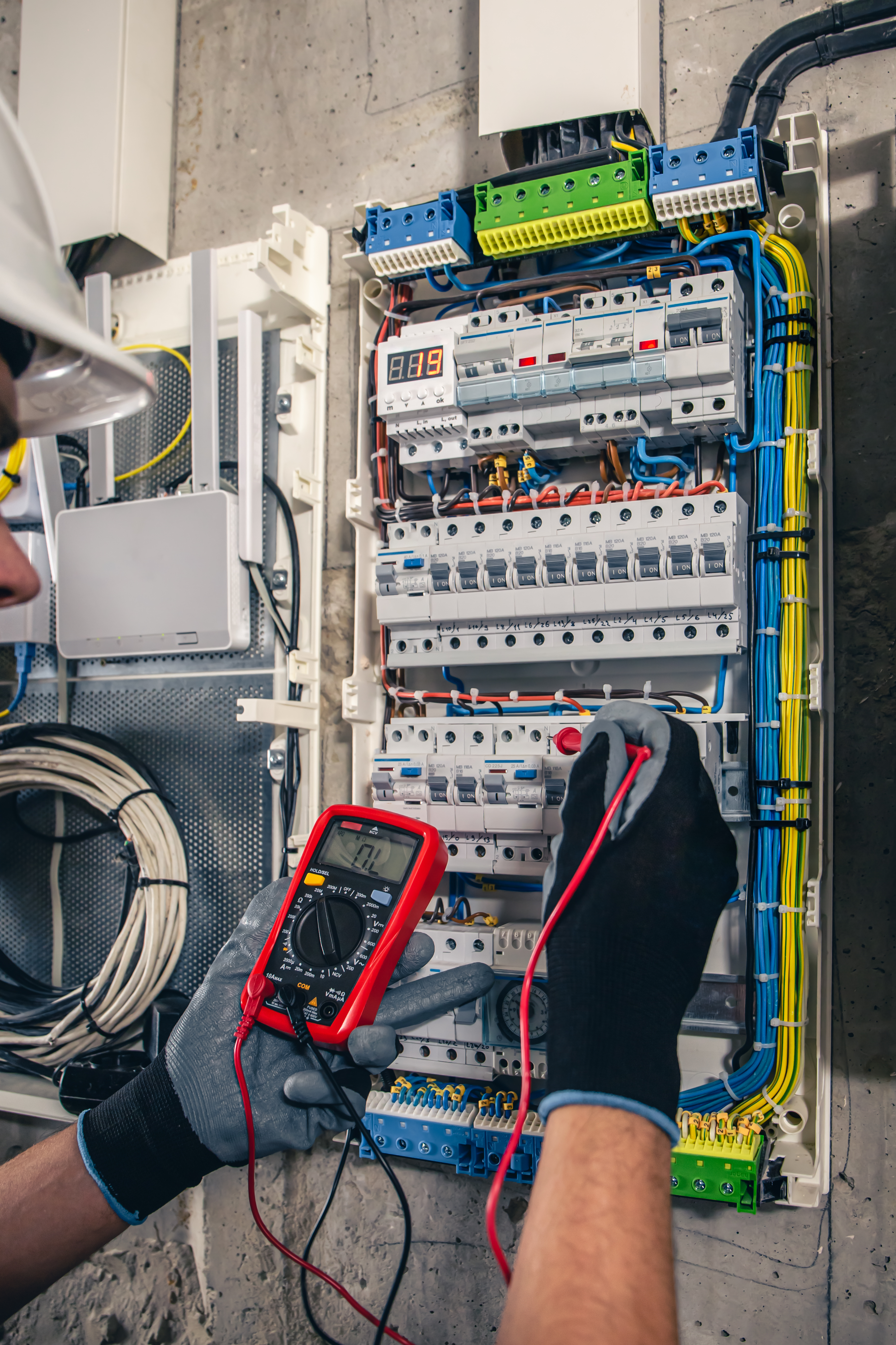 Man, an electrical technician working in a switchboard with fuses. Installation and connection of electrical equipment. Professional uses a tablet.