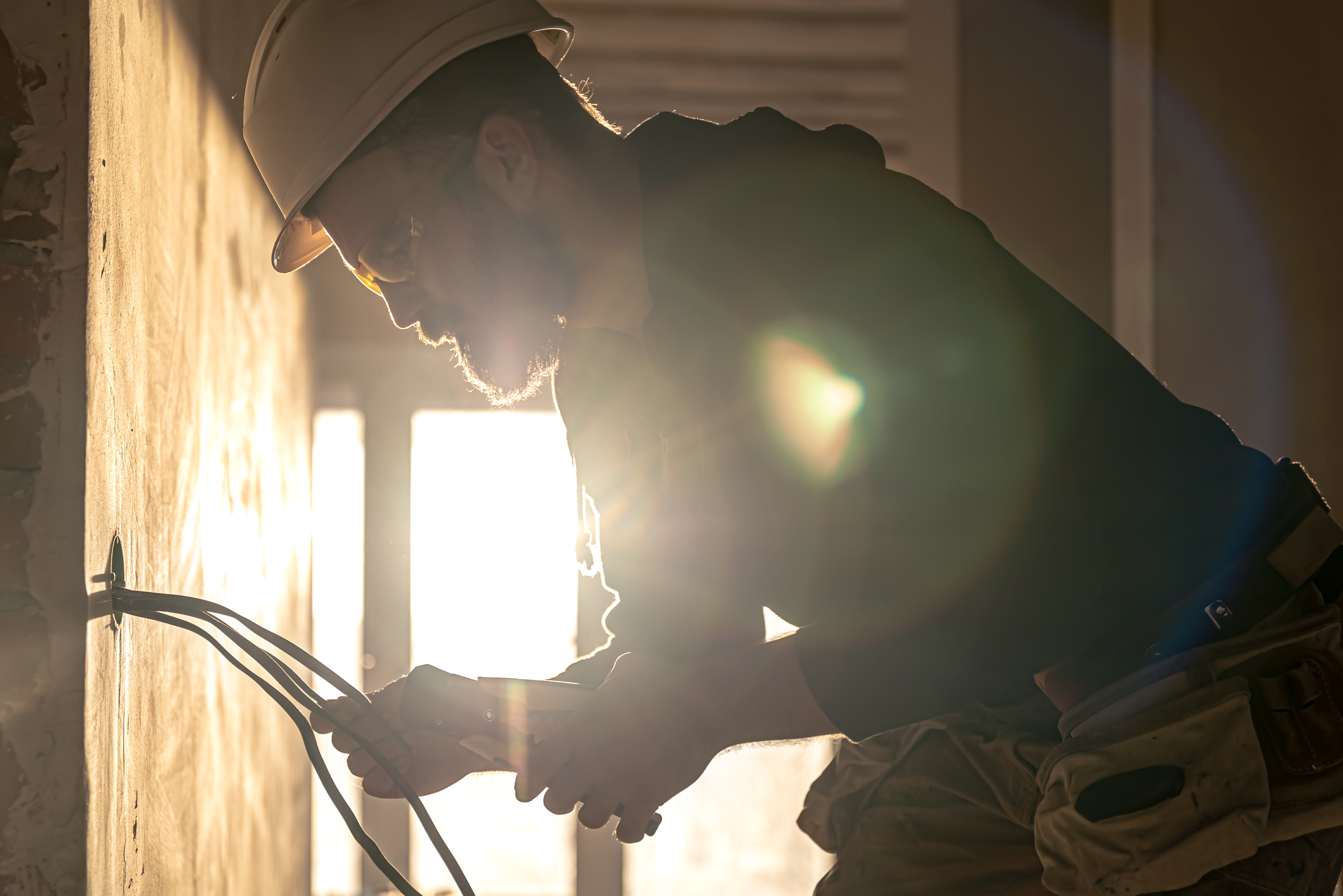 A construction electrician cuts a voltage cable during a repair.